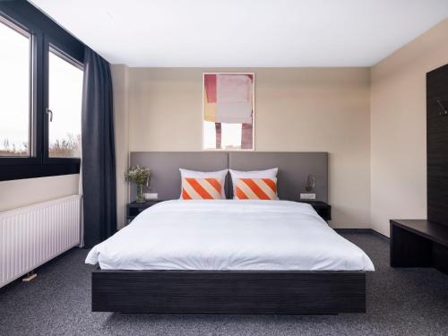 慕尼黑numa I Viktoria Apartments的一间卧室配有一张带橙色和白色枕头的大床