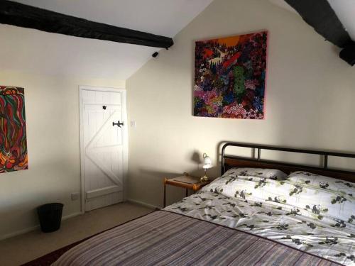 ClunLavender Cottage, 3 School Road, Clun, Shropshire的卧室配有一张床,墙上挂有绘画作品