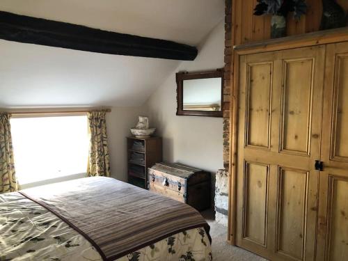 ClunLavender Cottage, 3 School Road, Clun, Shropshire的一间卧室配有一张床、一个梳妆台和一扇窗户。