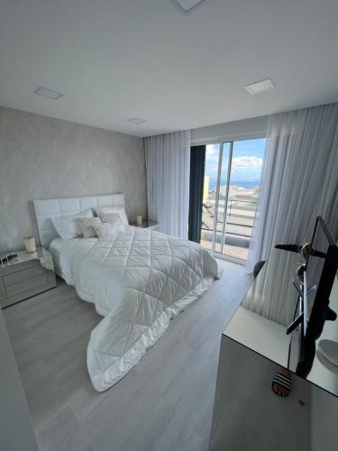 丰沙尔Apartamento Belo Horizonte的白色的卧室设有一张大床和一个窗户