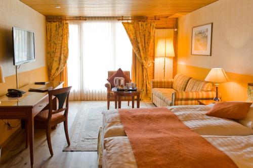 翁根Hotel Silberhorn - Residences & Spa Wengen的配有一张床和一张书桌的酒店客房