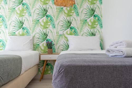 萨格里什Casa Epic的一间卧室配有两张床,铺有热带壁纸