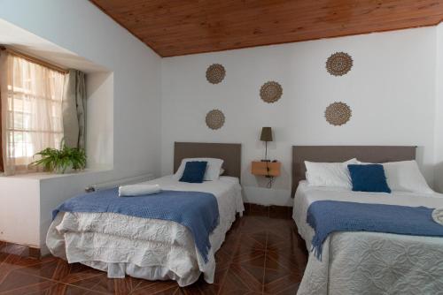 利纳雷斯Hotel Linares的配有白色墙壁和木制天花板的客房内的两张床
