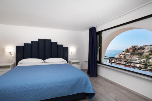 波西塔诺YourHome - H2O Marina Apt Sea View的一间卧室设有蓝色的床和大窗户