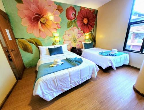 洛哈Hotel Virgen del Cisne的一间设有两张床的客房,墙上绘有鲜花