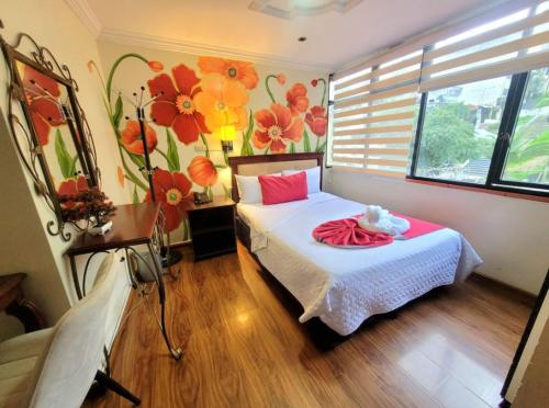 洛哈Hotel Virgen del Cisne的卧室配有一张墙上鲜花的床