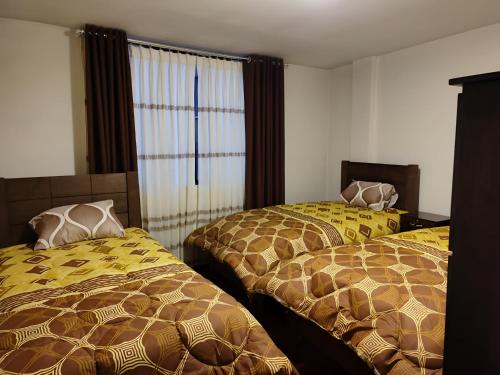 拉巴斯Departamento como en casa的一间卧室配有两张带黄褐色毯子的床