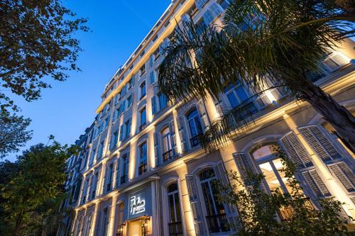 尼斯Hôtel Apollinaire Nice的一座白色的大建筑,前面有一棵棕榈树