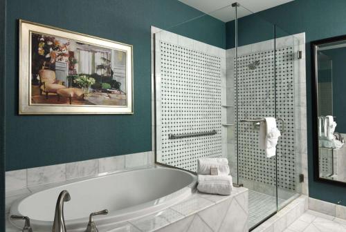 奥罗拉丹佛机场伍利经典套房酒店的带浴缸和玻璃淋浴间的浴室。
