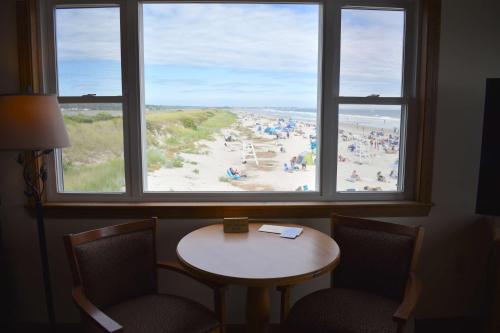 奥甘奎特Norseman Resort on the Beach的配有桌椅并享有海滩景色的客房