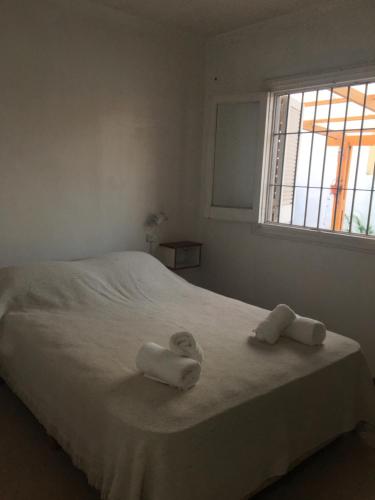 马德普拉塔Silvestre的卧室配有带2条毛巾的窗户,位于床上