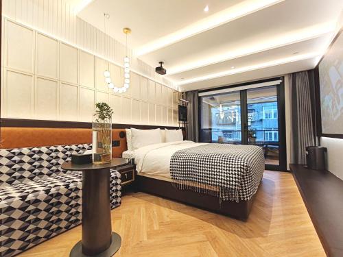 北京唐府酒店（北京三里屯工体店）的一间卧室配有一张床、一张桌子和一个窗户。