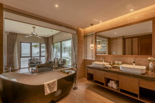 岘港KOI Resort & Residence Da Nang的一间带两个盥洗盆和大浴缸的浴室