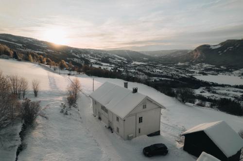 ØyerHafjell Farmhouse的雪中白房子,后面有太阳