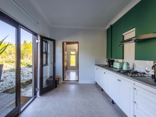 普利登堡湾Cliffside Suites的厨房配有白色橱柜和绿色墙壁