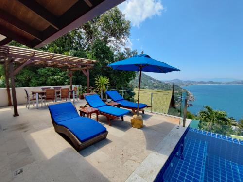 拉迈Sandalwood Luxury Villa Resort的一个带椅子和遮阳伞的庭院和一个游泳池