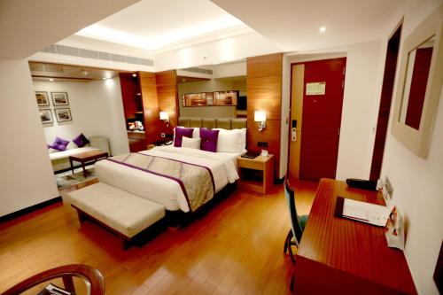 瓦拉纳西马丁酒店的大型酒店客房,配有一张床和一张书桌