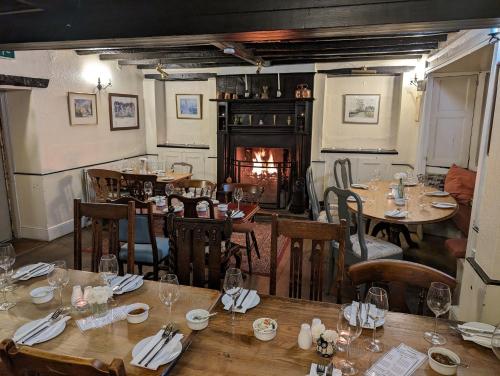北安普敦Bartholomew Arms的餐厅设有木桌、椅子和壁炉