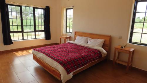 Archers PostSamburu Dik-Dik House & Susuk Self-catering Cottage的一间卧室配有一张带红色毯子的床和两个窗户。