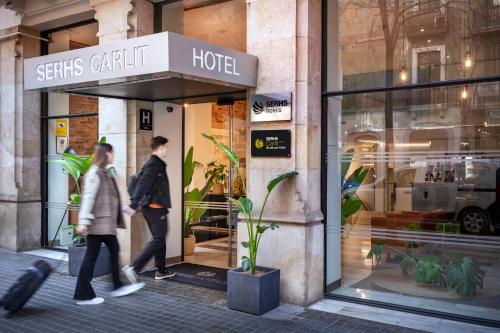 巴塞罗那SERHS Carlit Boutique Hotel的两个人在商店前走