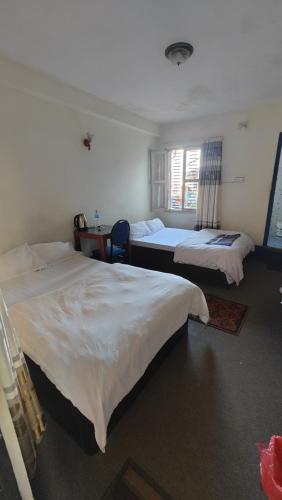 DailekhHotel Mansarovar的一间卧室设有两张床、一张桌子和一个窗口。