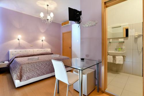 利多迪耶索罗HOTEL BLUMARIN的一间卧室配有一张床和一张玻璃桌,还设有一间浴室