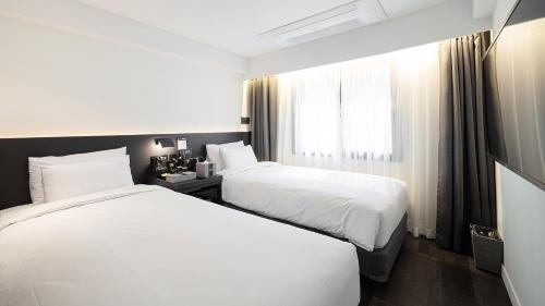 束草市Moyen Hotel的酒店客房设有两张床和窗户。
