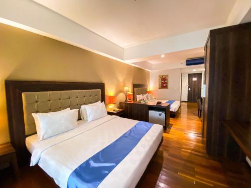 日惹Luxury Malioboro Hotel的一间卧室配有一张大床和一张书桌