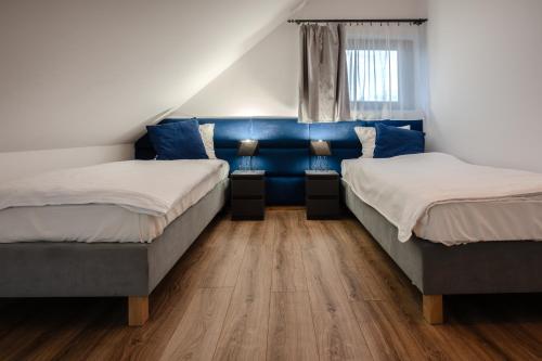 Dąbrówka SzczepanowskaApartament w Winiarni的配有蓝色墙壁和木地板的客房中的两张床