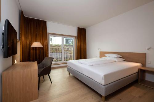 林茨Best Western Hotel Spinnerei Linz的一间卧室配有一张床、一张书桌和一个窗户。