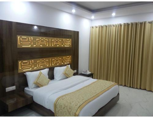 安巴拉Hotel Sobti Plaza, Ambala, Haryana的一间卧室配有一张大床和木制床头板
