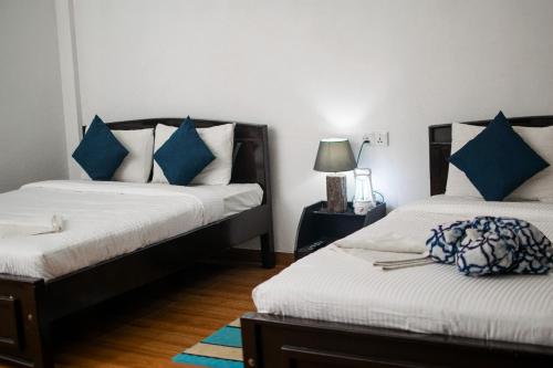 埃拉ESSPEEDY Hill Forest Cottages and Yoga Centre的一间卧室配有两张带蓝白色枕头的床