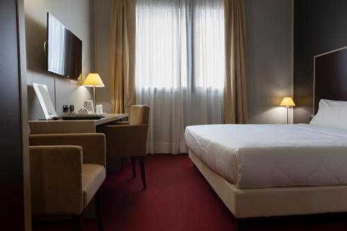 都灵奥林匹克艺术酒店的配有一张床和一张书桌的酒店客房