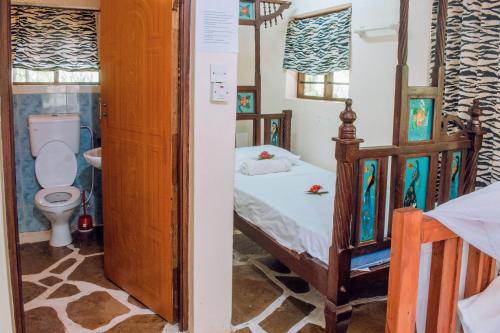 迪亚尼海滩Kijani Cottages In Diani的一间小卧室,配有一张床和一个卫生间