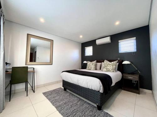 德班Cosy Comfort Guest Suit的一间卧室配有一张床、镜子和一张书桌