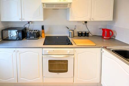布里斯托Ellan Hay by StayStaycations的厨房配有白色橱柜和炉灶烤箱。