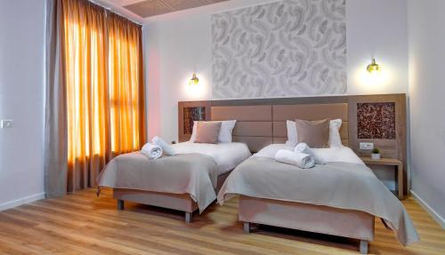 布加勒斯特SIR FUNDENI HOTEL的一间卧室配有两张带白色床单的床