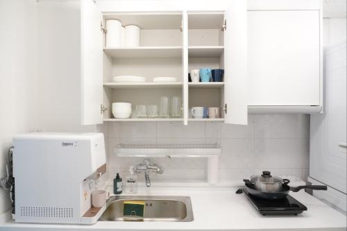首尔Coco Stay的厨房配有白色橱柜和水槽