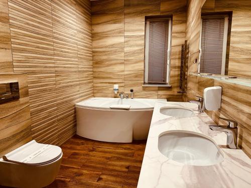 Stara BlotnicaHotel Rubin的一间带两个盥洗盆、浴缸和卫生间的浴室