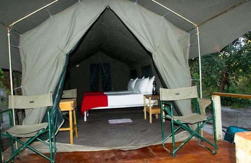 KhwaiCandies Vacation Cottage Khwai的帐篷配有一张床和两把椅子