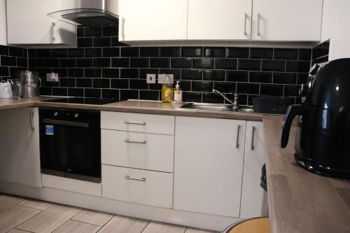 利物浦Kop View的厨房配有白色橱柜和黑色瓷砖墙