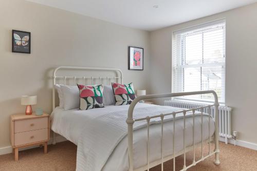 迪尔Sunbeam Cottage的卧室配有带枕头的白色床和窗户。