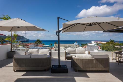 科苏梅尔Coralia Hotel Cozumel的一个带沙发和遮阳伞的庭院和大海