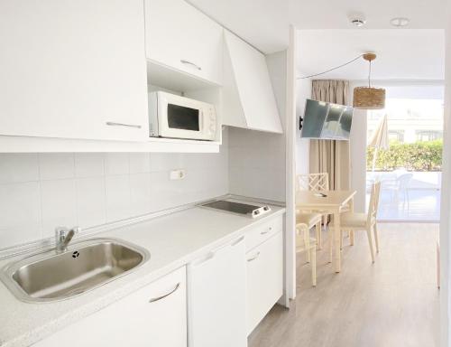 卡拉米洛Apartamentos Morito Beach的白色的厨房配有水槽和桌子