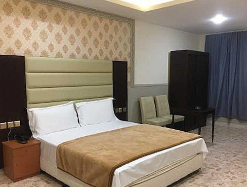 拉斯阿尔卡麦OYO Al Taj Rest House的一间卧室配有一张大床和一把椅子