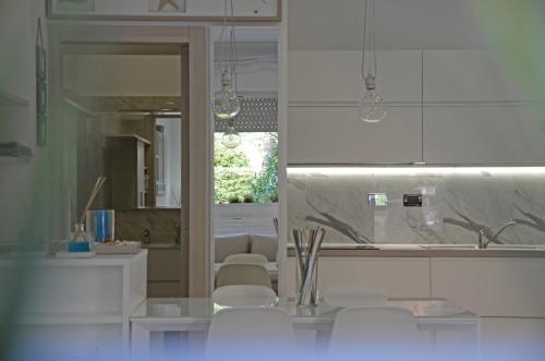 莱里奇Appartamento Emozione Mare Blu San Terenzo的厨房配有白色橱柜和白色椅子