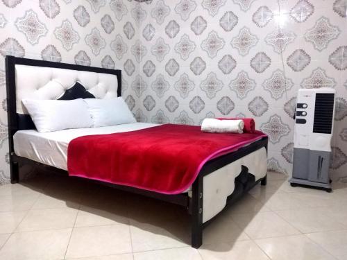 坦坦Aziz House 2的一间卧室配有一张带红色毯子的床