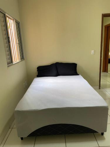 阿拉瓜伊纳Refúgio Aconchegante e Espaçoso的一张位于小客房内的床铺,配有白色床垫