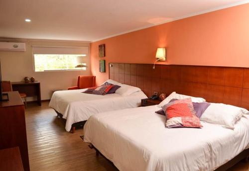 MéridaHotel La Pedregosa的橙色墙壁的酒店客房内的两张床