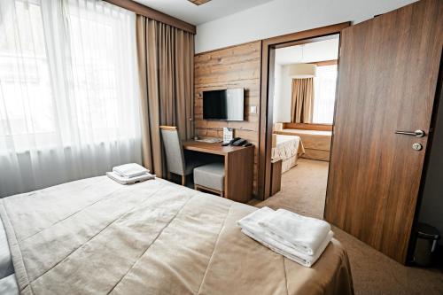 多纳瓦利Šport Hotel *** Donovaly的酒店客房配有一张床和一张书桌及一台电视